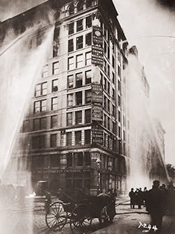 Fire hoses spray water on the upper floors of the Asch Building (housing the Triangle Shirtwaist Company) on Washington and Greene Streets, during the fire in New York City on March 25, 1911.