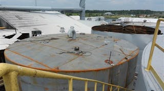 An explosion of what was thought to be nonhazardous materials blew the top off of this tank, killing one worker and severely injuring another.