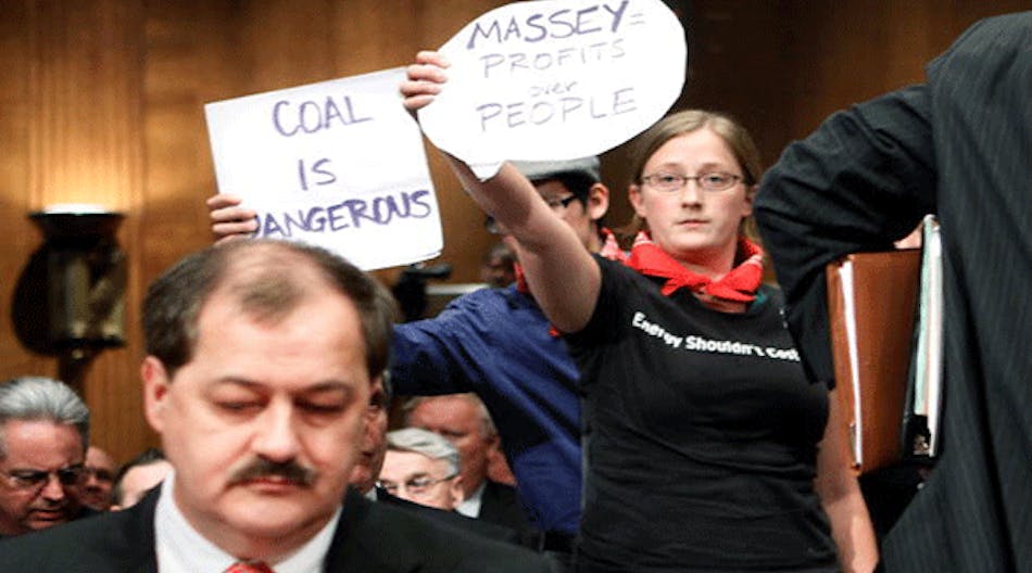 Protester Kate Rooth (R) holds a sign as Chairman and CEO of Massey Energy Company Don Blankenship (L) prepares to testify for a hearing before the Labor, Health and Human Services, Education, and Related Agencies Subcommittee of the Senate Appropriations Committee May 20, 2010 on Capitol Hill in Washington, DC. The hearing was to examine issues regarding the safety of coal mining.