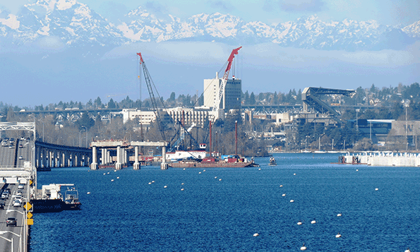 With the Olympic Mountains in the background construction on the West Connection Bridge progresses on Lake Washington in Seattle Once complete the bridge will connect the new floating bridge to the existing SR 520 west approach