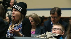 Desiree Duell (L), reacts to testimony from Michigan Gov. Rick Snyder, while her 10-year-old son David Henderson sits nearby, during a House Oversight and Government Reform Committee hearing, about the Flint, Mich. water crisis, on Capitol Hill March 17 in Washington, DC. The committee was examining how lead ended up in the public drinking water in Flint.