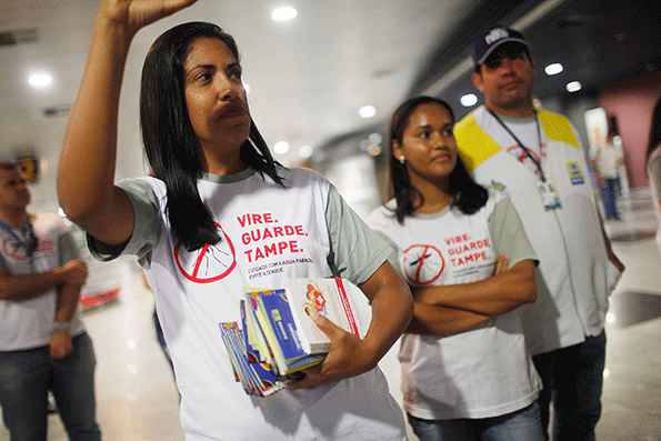Health workers pass out information on mosquito protection to people arriving in the baggage claim area at Guararapes Gilberto Freyre International Airport on Feb 4 in Recife Pernambuco state Brazil Officials say as many as 100000 people may have already been exposed to the Zika virus in Recife