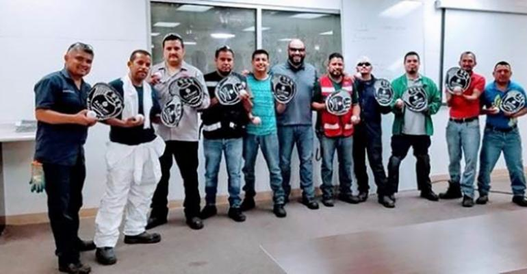 Employees at a meeting on hand safety received foam baseball mitts