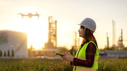 Drone flying over oil refinery plant during site survey.