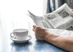 person reading newspaper near window while drinking a hot beverage person reading newspaper near window while drinking a hot beverage