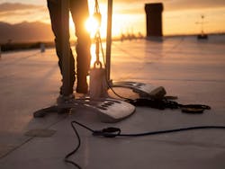 close up of fall protection tethering, workers' legs and sunset in the background close up of fall protection tethering, workers' legs and sunset in the background