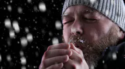 Man wearing a hat and coat shivering in the cold