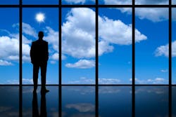 businessman silhouette looking through floor to ceiling windows of clouds and a bright blue sky businessman silhouette looking through floor to ceiling windows of clouds and a bright blue sky