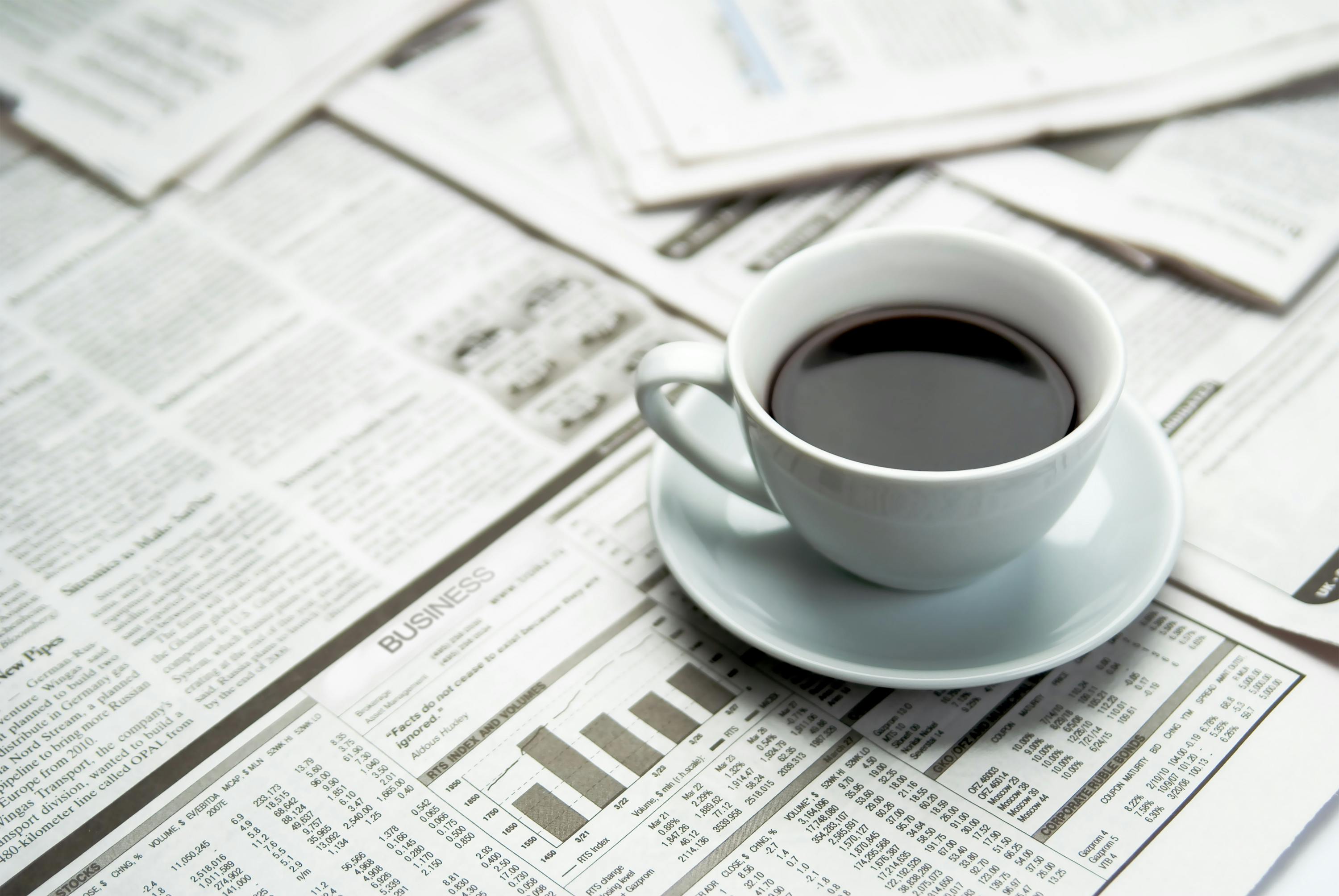 Open newspaper and a cup of coffee