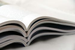 magazines open and stacked on top of one another magazines open and stacked on top of one another