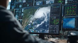 Image of multiple computer screens monitoring or tracking the weather with a person in the foreground Image of multiple computer screens monitoring or tracking the weather with a person in the foreground