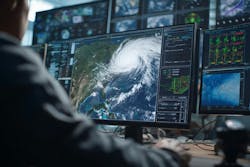 Image of multiple computer screens monitoring or tracking the weather with a person in the foreground Image of multiple computer screens monitoring or tracking the weather with a person in the foreground