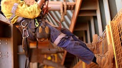 Wide angle picture of male worker wearing full safety harness while working at height Wide angle picture of male worker wearing full safety harness while working at height