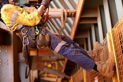 Wide angle picture of male worker wearing full safety harness while working at height Wide angle picture of male worker wearing full safety harness while working at height