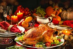 Picture of a tablescape with a turkey on a platter and formal place settings, gravy boat, candles, wine glasses and pumpkins in the background. Picture of a tablescape with a turkey on a platter and formal place settings, gravy boat, candles, wine glasses and pumpkins in the background.