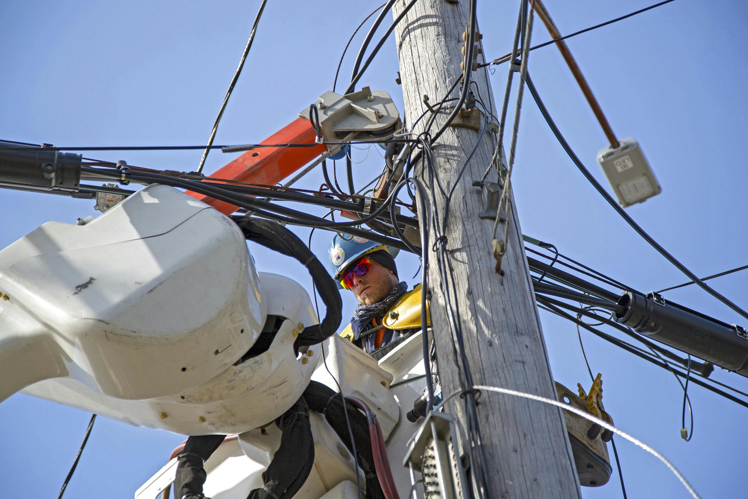 lineman working out in the field on electrical wires at height in a cherry picker