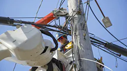 lineman working out in the field on electrical wires at height in a cherry picker