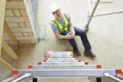 image of ladder in foreground with a man in hard hat and hi-vis safety vest clutching his knee on the ground image of ladder in foreground with a man in hard hat and hi-vis safety vest clutching his knee on the ground