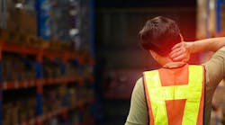 worker in a warehouse wearing a hi-vis vest with his back to camera holding his neck in pain worker in a warehouse wearing a hi-vis vest with his back to camera holding his neck in pain
