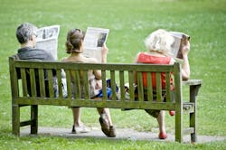 picture of a middle-aged man, young woman and older woman sitting on a park bench reading the newspapers with their back to the camera picture of a middle-aged man, young woman and older woman sitting on a park bench reading the newspapers with their back to the camera