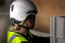 Picture of a woman in a hi-vis safety vest and Mips Type 2 safety helmet at a construction site looking away from the camera Picture of a woman in a hi-vis safety vest and Mips Type 2 safety helmet at a construction site looking away from the camera