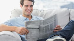 young man sitting on couch reading the newspaper young man sitting on couch reading the newspaper