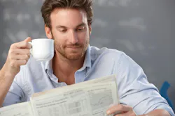 man sitting and holding an espresso cup in one hand and the newspaper in another man sitting and holding an espresso cup in one hand and the newspaper in another
