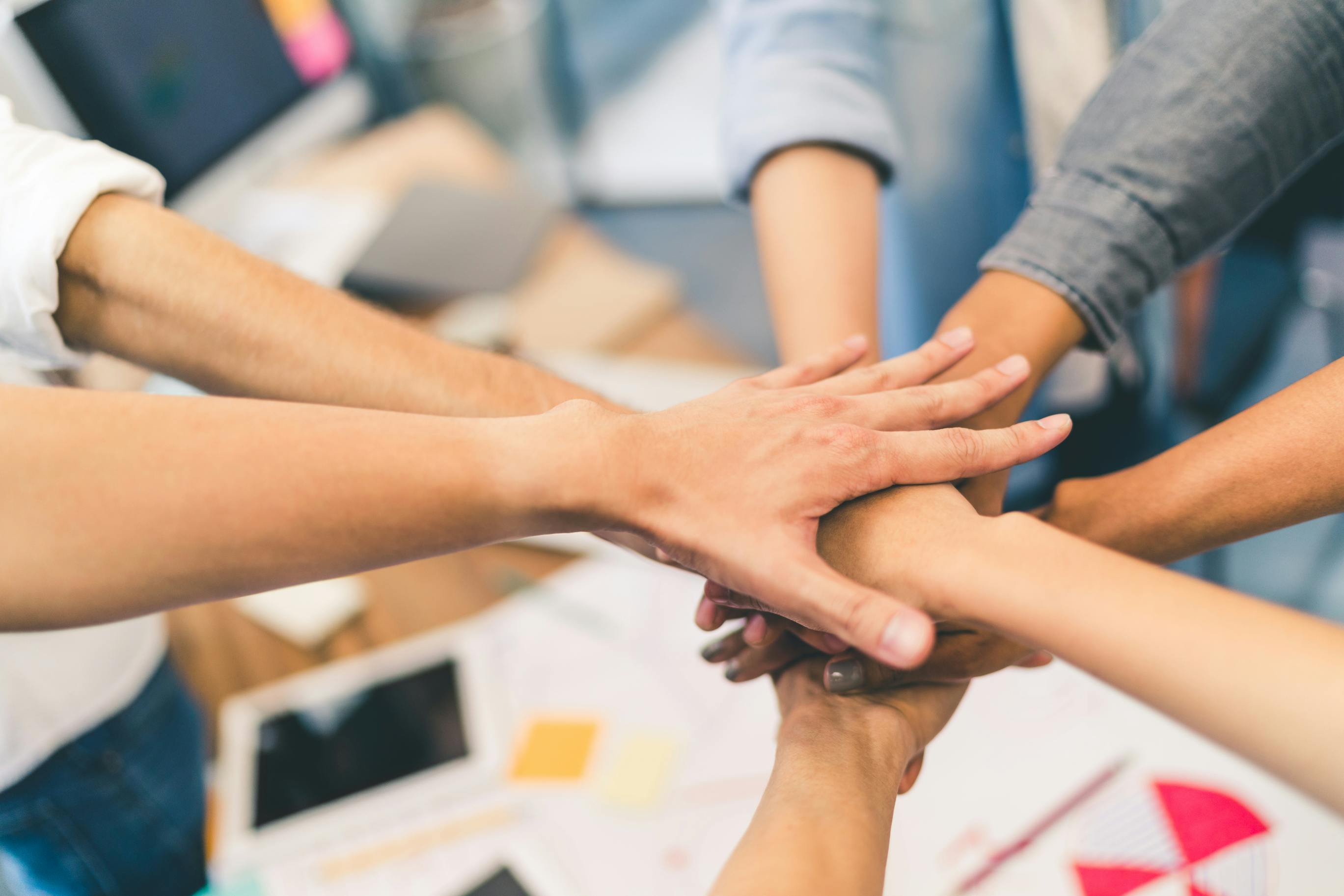 people putting hands in a circle, symbolizing teamwork and unity