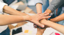 people putting hands in a circle, symbolizing teamwork and unity