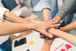 people putting hands in a circle, symbolizing teamwork and unity