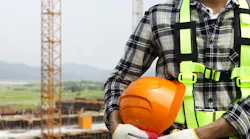 picture of construction worker wearing hi-vis vest and gloves holding a hard hat