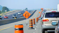 picture of cars bumper to bumper on a highway with one lane closed for construction, with signage