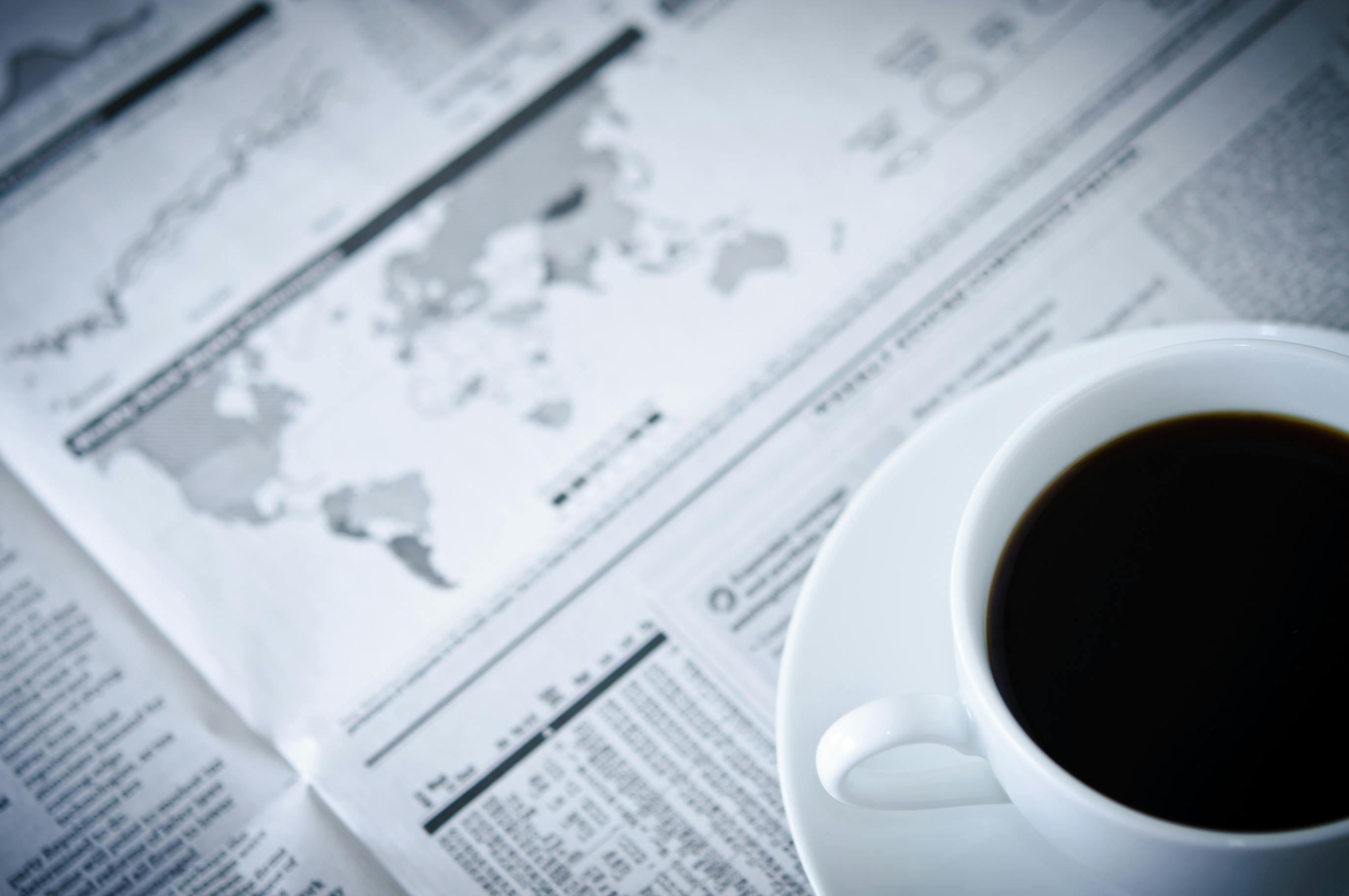 picture of coffee cup and saucer on top of a newspaper